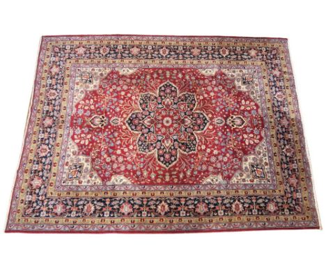 A large deep red ground Persian carpet, the central floral medallion enclosed by conforming spandrels and a rich blue border,
