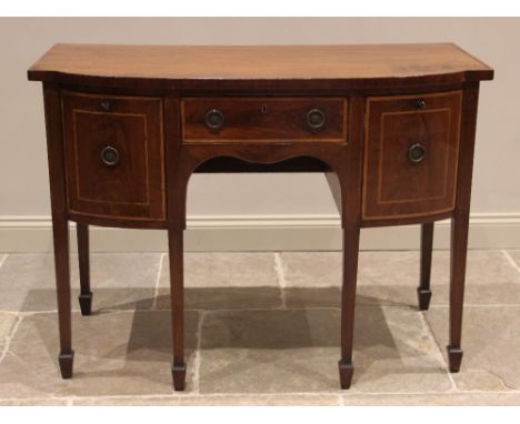 A George III mahogany bow front sideboard, the crossbanded top above a central, oak lined frieze drawer, flanked by a cellare