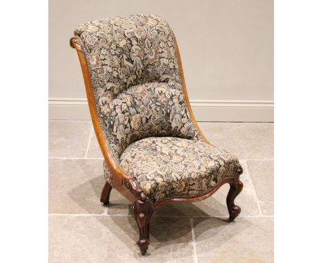 A Victorian mahogany low seat nursing chair, in tapestry style fabric, the curved side rails carved with foliate detail and e