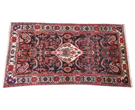 A deep ground Persian Ardebil carpet, in orange, brown and red colourways, the central petal shaped medallion within a traili