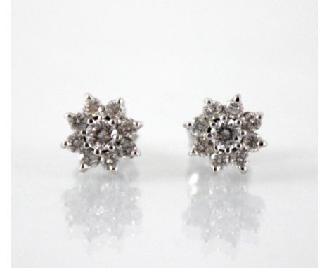 A pair of diamond floral cluster earrings, each comprising a central round brilliant cut diamond weighing approximately 0.10 