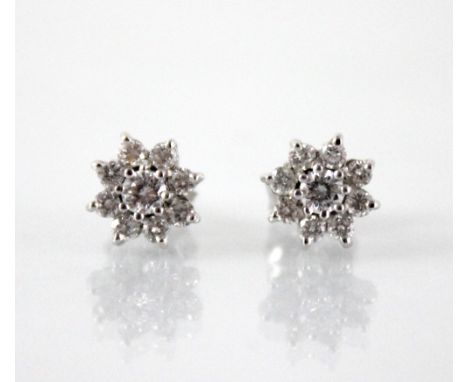 A pair of diamond floral cluster earrings, each comprising a central round brilliant cut diamond weighing approximately 0.10 