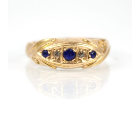 An Edwardian diamond and blue stone 18ct gold ring, the central navette shaped panel set with round mixed cut blue stones and