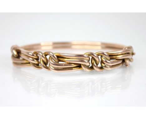 An early 20th century knot design hinged bangle, the front section designed as interwoven knots, tongue and box snap clasp fa
