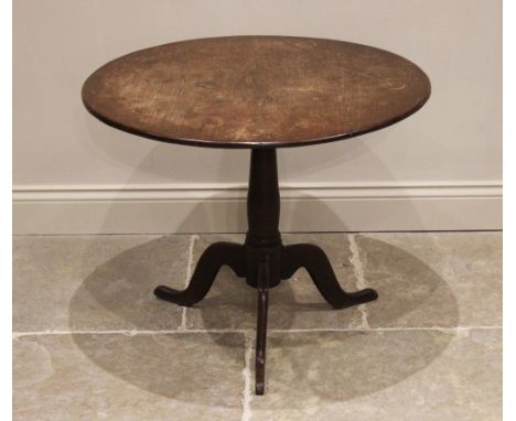 A George III oak tripod table, the circular top raised upon a ring turned baluster column extending to three down swept suppo