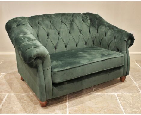 A green velour two seater Chesterfield settee, contemporary, the deep set arms and button back enclosing the single cushion s