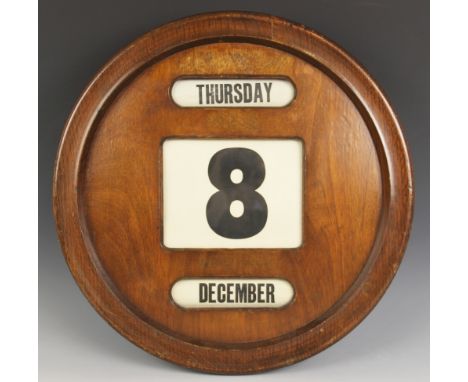 A circular mahogany perpetual wall calendar, mid 20th century, the front with three glazed apertures showing the day, date, a