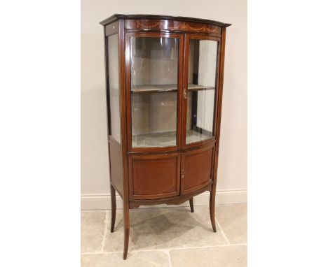 An Edwardian mahogany bowfront display cabinet, the frieze inlaid with an Adam style urn and harebell swags over a pair of gl