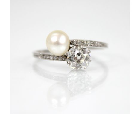 An early 20th century diamond and pearl ‘moi et toi’ ring, comprising an old cut diamond measuring 5.7mm x 5.7mm x 3.5mm, the