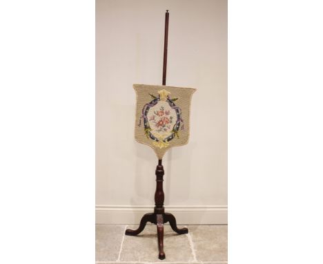 A Victorian mahogany pole screen, the shield shaped floral tapestry screen upon a slender pole and three leaf carved cabriole