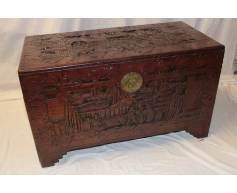 An Eastern carved camphor wood rectangular trunk with  figure and landscape decoration and brass mounts, internal Hong Kong l