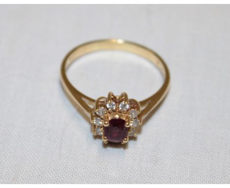 An 18ct gold dress ring set a central ruby surrounded by diamond chips (3.3g)