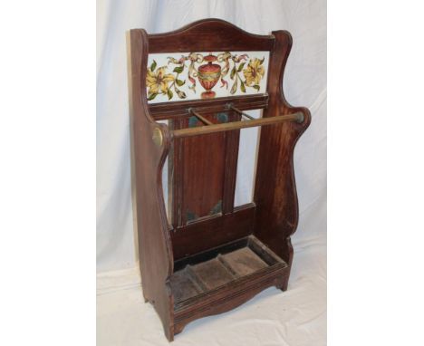A Victorian walnut stick-stand with brass dividing rail and ceramic tiled back on standard supports, 36½" high