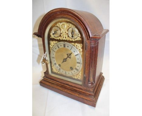 A German bracket clock with silvered and gilt arched dial in polished oak arched case