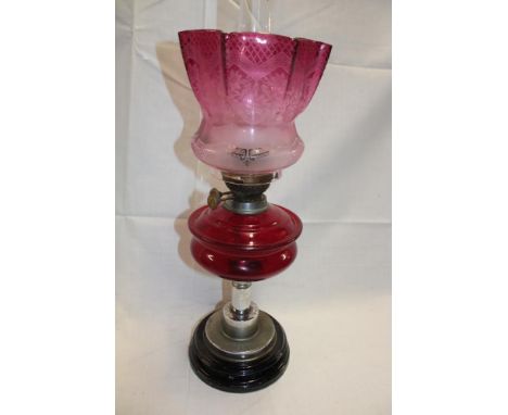 An old chromium plated brass mounted oil lamp with ruby tinted glass reservoir and cranberry tinted glass shade