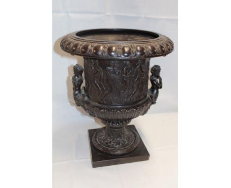 A 19th century bronze circular two-handled classical-shaped urn decorated in relief with numerous dancing figures on tapered 