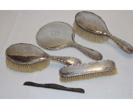 A silver four-piece dressing set comprising a pair of hair brushes, clothes brush and hand mirror together with a comb back, 