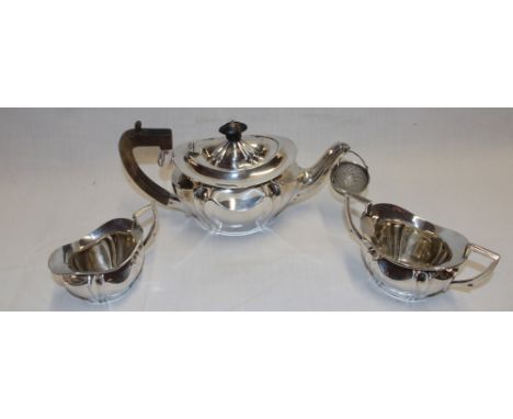 A late Victorian silver three-piece tea set comprising an oval tea pot with raised decoration and polished wood angular handl
