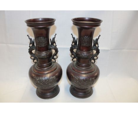 A pair of 19th century Japanese bronze two-handled vases with raised dragon decoration and scroll handles, 14" high