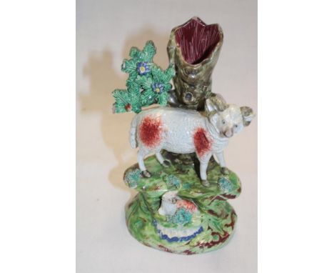 A 19th century Staffordshire pottery figure by Walton depicting a sheep and lamb below a tree trunk spill (af), 7½" high