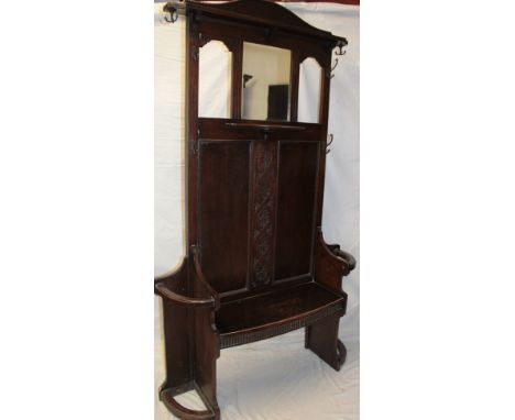 A 1930's/40's carved oak hall stand with central seat flanked by curved stick stands, the upper centre with bevelled rectangu
