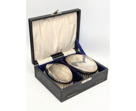 A pair of Early 20th Century silver plated vanity brushes in case.   (6)