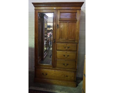 A Late Victorian Walnut Wardrobe, Having a cuboard door above three small drawers, flanked by a mirrored door, above a large 