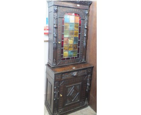 A Victorian carved oak cupboard with decorated lead light door and lion mask carving over single drawer and cupboard below