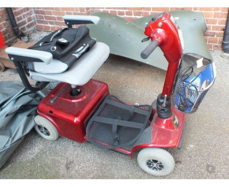 A red mobility scooter with charging lead and cover