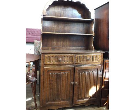 An oak dome top open shelf dresser with linen fold carving