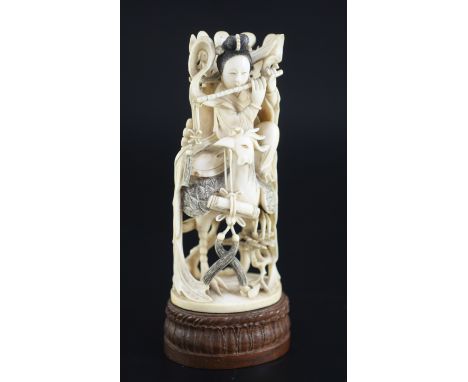 A Chinese ivory figure of the goddess He Xiangu, early 20th century, playing a flute and riding a fenghuang (phoenix), 21.5cm