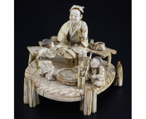 A Japanese ivory okimono of a man and two boys, signed Shomi, Meiji period the man holding a fan and a pipe, seated on a benc