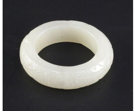 A Chinese white jade bangle or ring, carved in low relief with a phoenix and another mythical beast, diameter 5.7cm