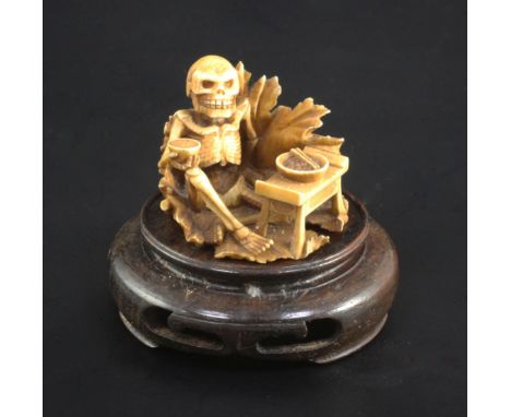 A Japanese ivory netsuke of a skeleton, early 20th century, signed Sei..? seated on a lotus leaf and apparently eating food, 