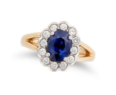 A SAPPHIRE AND DIAMOND CLUSTER RING in 18ct yellow gold, set with an oval cut sapphire of approximately 2.41 carats in a clus