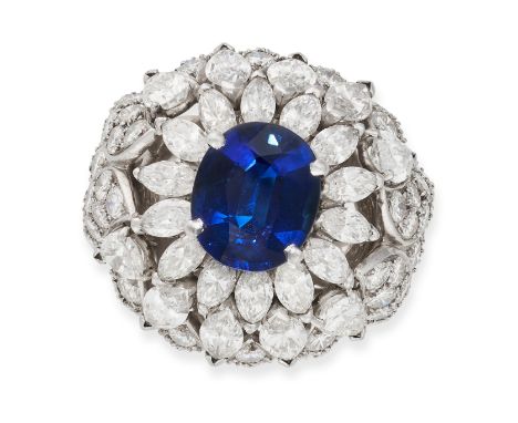 A VINTAGE SAPPHIRE AND DIAMOND BOMBE RING, 1970S designed as a stylised floral cluster, set with an oval cut sapphire of appr