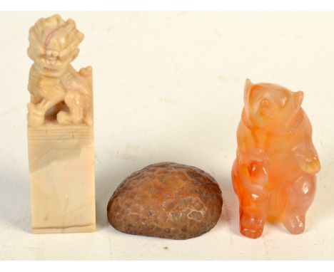 A carved jade or other hard stone model of a bear seated on its hind quarters and two other stone pieces. 4.7cm.