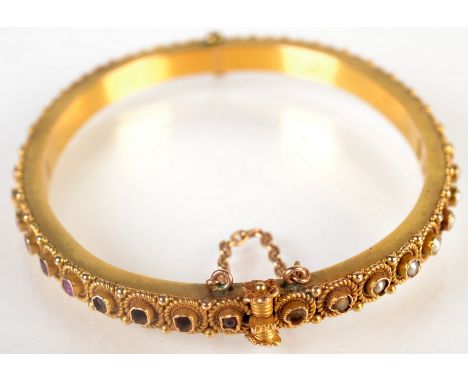 A high purity gold bangle, one half set with pearls, the other rubies within spiral wire mount. 