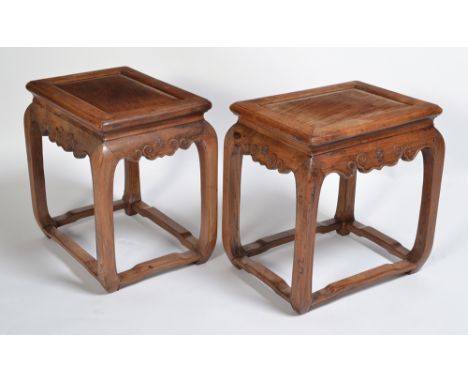 A pair of 19th century Chinese huanghulai wood stools, the top of each with a floating panel, the aprons carved with simple s