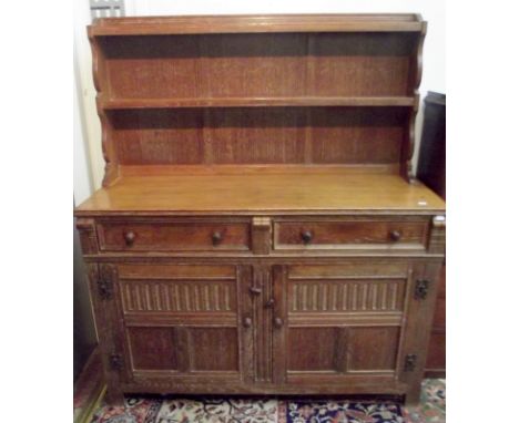 An Arts and Crafts light oak dresser with open low rack, retailed by Maple, width 123.5cm, height 144cm.