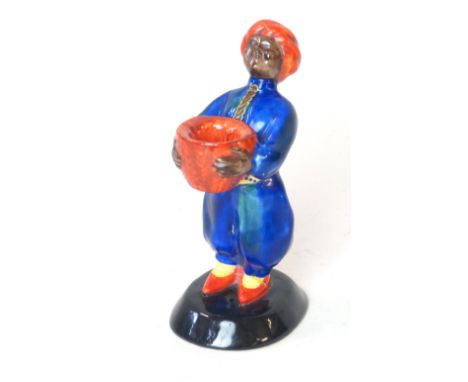 A Clarice Cliff Wilkinson pottery candle holderModelled in the form of an Arab male holding a basket, painted in reds, blues,