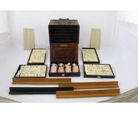 AN ORIENTAL CARVED HARDWOOD CASE MAH-JONG SET, with bone and bamboo playing tablets, the box has sliding panel revealing five