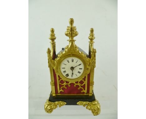 A LATE 19TH CENTURY GOTHIC REVIVAL DESK CLOCK, cast brass tracery mounted case with red fabric panels raised on cast acanthus