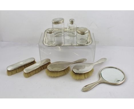 ADIE BROTHERS LIMITED A SILVER DRESSING TABLE SET, comprising a vanity hand mirror, two pairs of brushes, four silver topped 