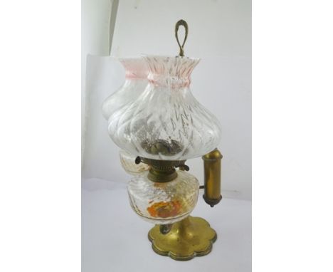 A VICTORIAN BRASS FRAMED DOUBLE TABLE TOP OIL LAMP, cherub mounted, with central carrying handle, on circular petal rimmed ba