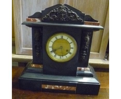 A LATE 19TH CENTURY BLACK SLATE EIGHT DAY MANTEL CLOCK on gong strike, with rouge marble panels and cast metal mask decoratio