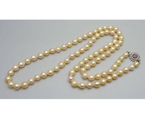 A string of pearls with a white metal and ruby set flower cluster clasp, 76cm, 66g