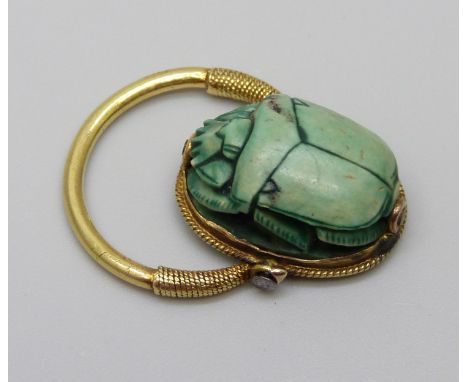 An Egyptian yellow metal set scarab beetle ring with carved scene verso, 5.1g, size K