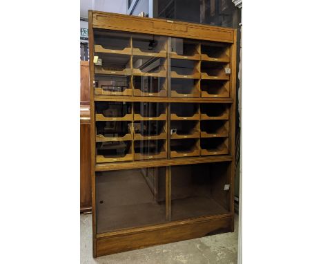 HABERDASHERY CABINET, 49cm D x 200cm H x 130cm W, oak by Dudley &amp; Co Ltd, bears plaque, with six sliding glass doors and 