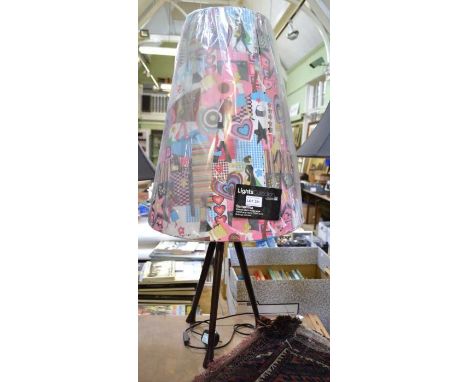 A three legged table lamp with multi-coloured shade
